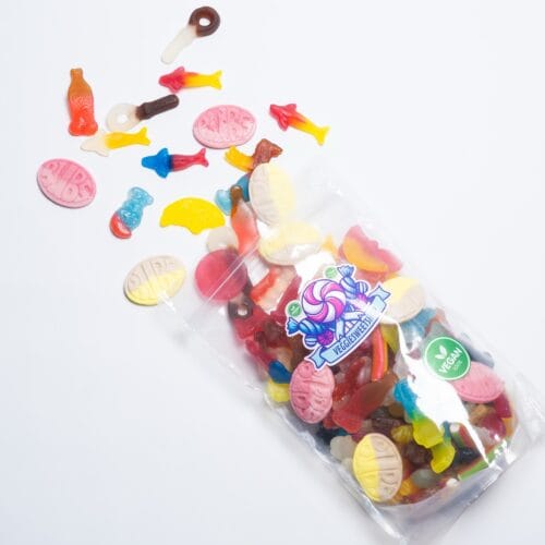 Open zak veggie snoep met uitgestrooide snoepjes op witte achtergrond